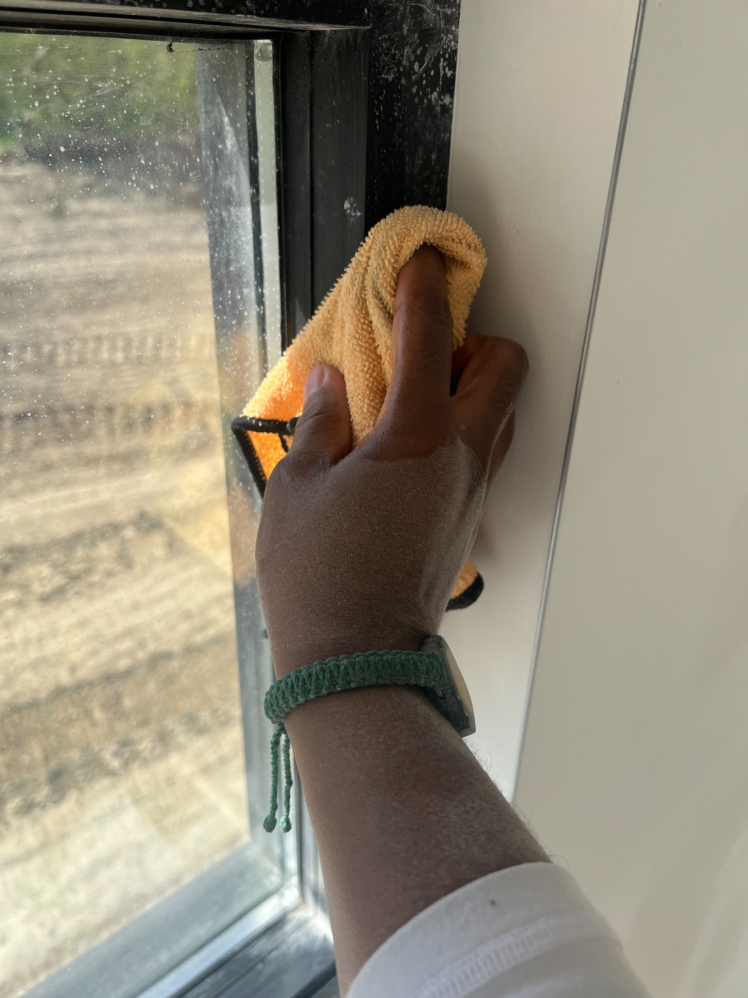 Amber Walls working along a window edge with a cloth